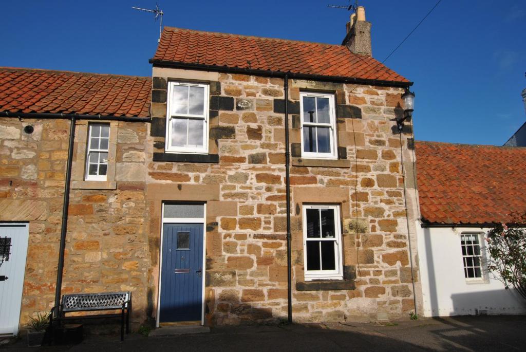 an old stone house with a blue door at Willow Cottage- charming cottage in East Neuk in Pittenweem