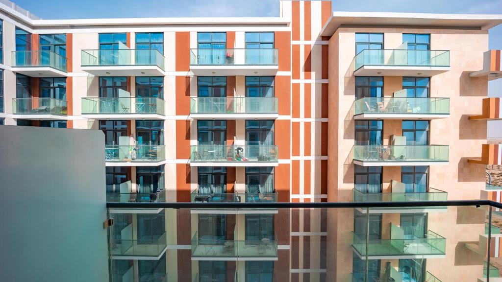 an apartment building with its reflection in the window at Sleek Studio in Celestia Tower A Dubai South Dubai by Tanami Holiday Homes in Dubai