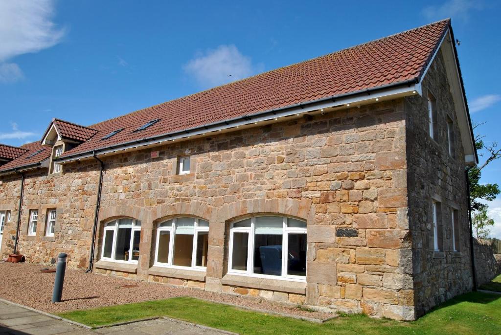 a brick building with white windows and a red roof at Seaview Steading-spacious home in rural location in Crail