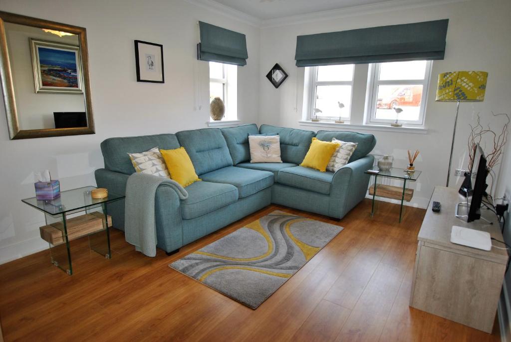 a living room with a blue couch and a table at The Neuk- contemporary coastal apartment in Anstruther