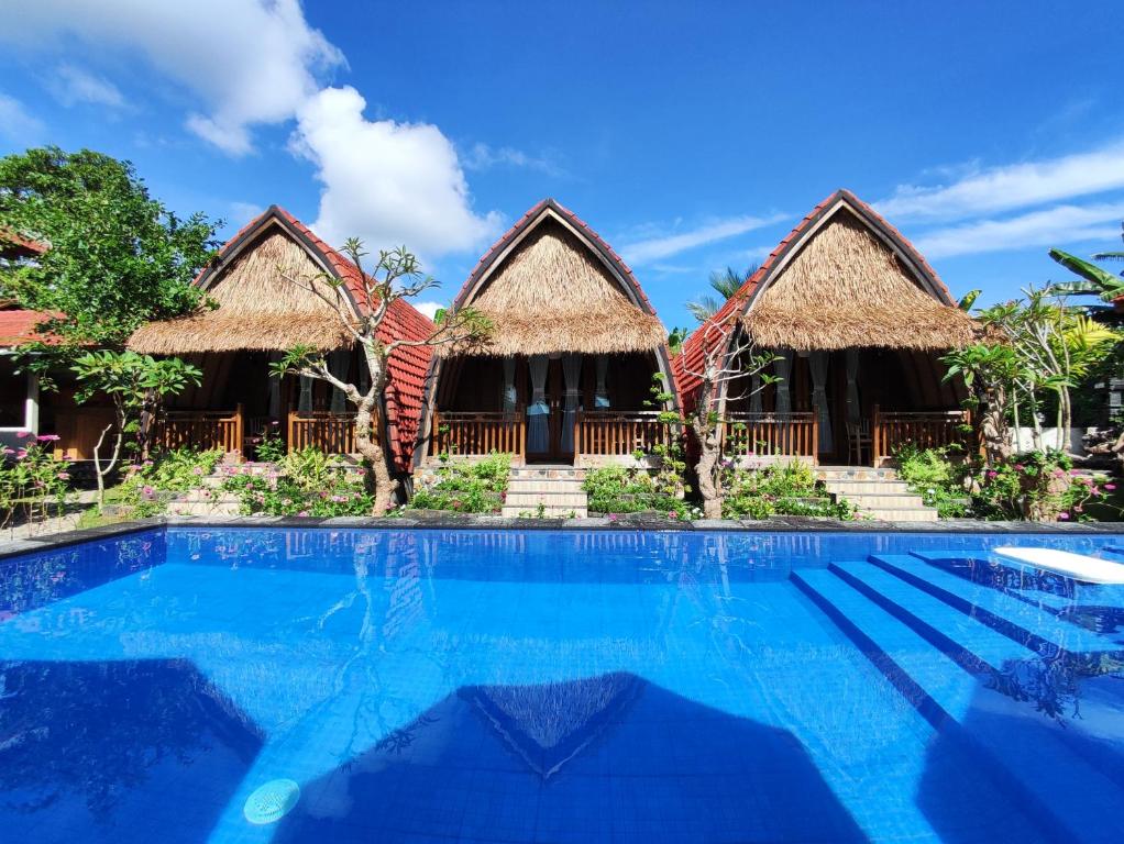 a resort with a swimming pool and two huts at Grand Cory in Nusa Penida