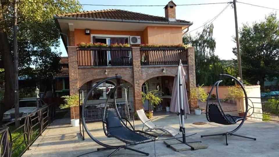 a playground with chairs and an umbrella in front of a house at Vila Soleil in Smederevo