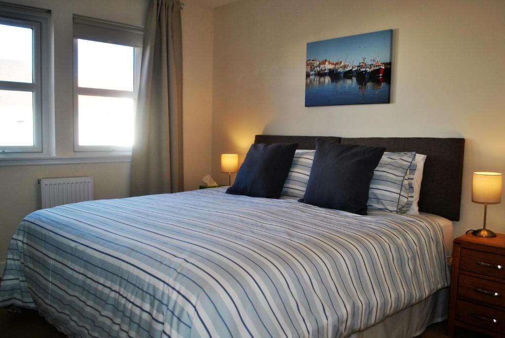 a bedroom with a bed with a blue and white comforter at Forth View- stylish upper apartment with sea views in Anstruther
