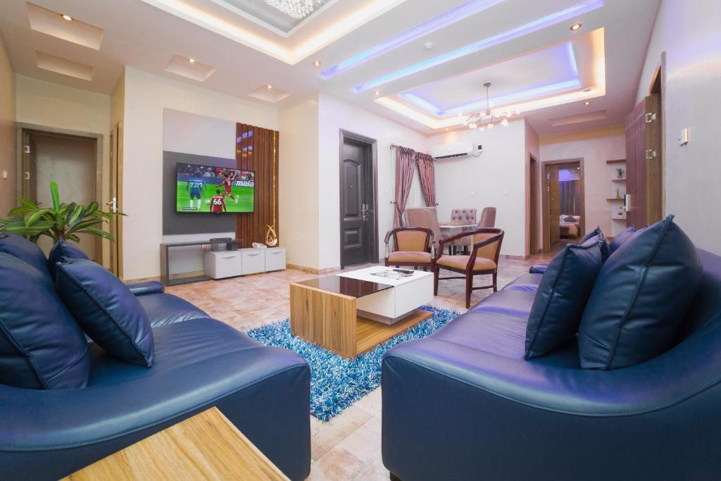 een woonkamer met twee blauwe banken en een tv bij God's Touch Apartments Signature in Lagos