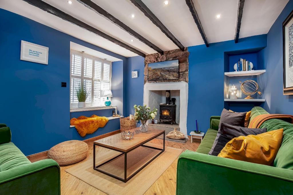 a living room with blue walls and a couch and a table at Honeybee Cottage- stunning home on Fife coast in Anstruther