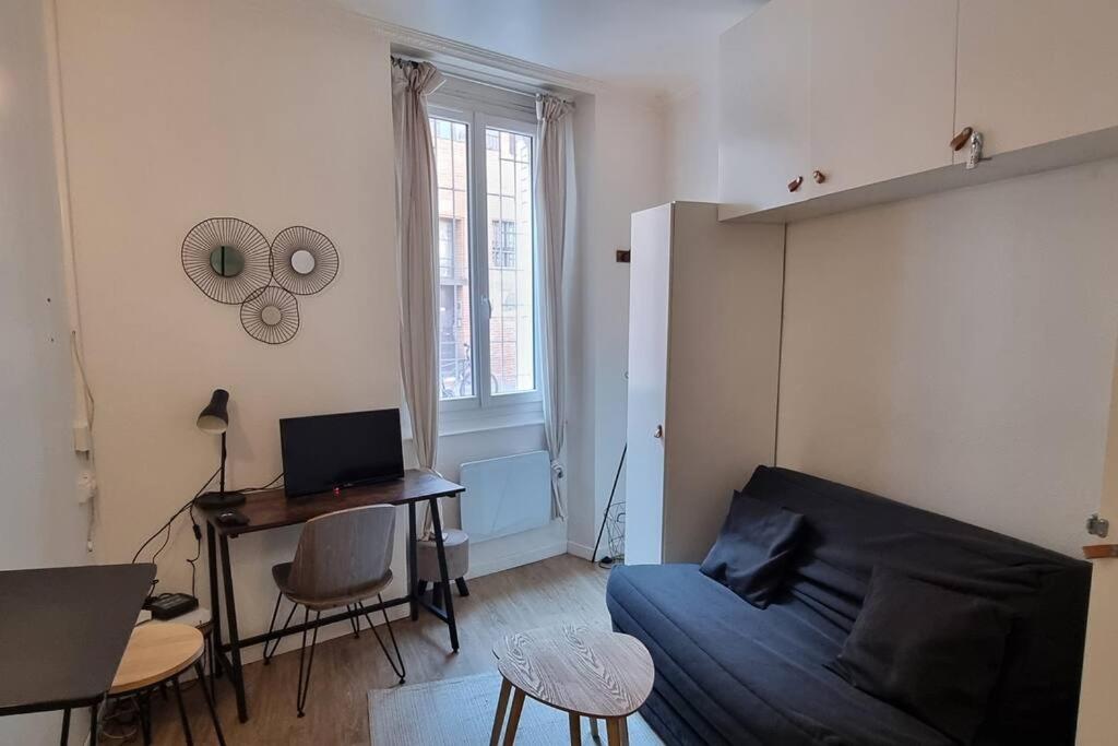a living room with a couch and a desk with a laptop at Studio en RDC - Quai de Garonne - Capitole - Wifi in Toulouse