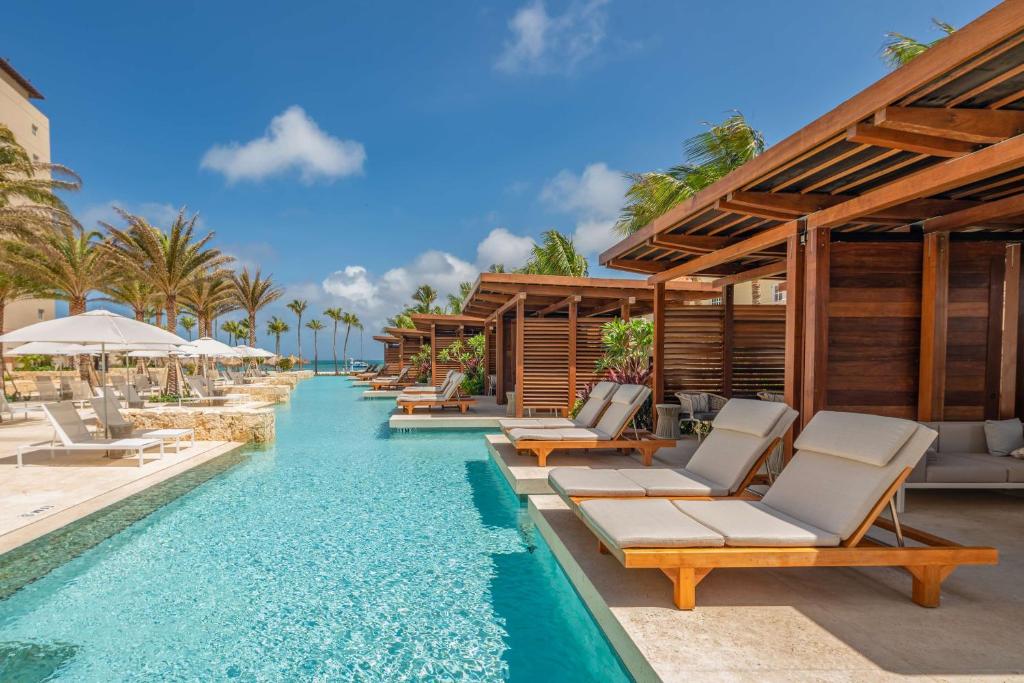 een overloopzwembad van het resort met ligstoelen en parasols bij Hyatt Regency Aruba Resort & Casino in Palm-Eagle Beach