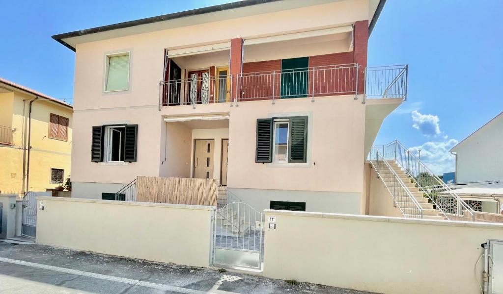 a white house with a balcony and stairs at Trilocale Jolly in Marina di Bibbona