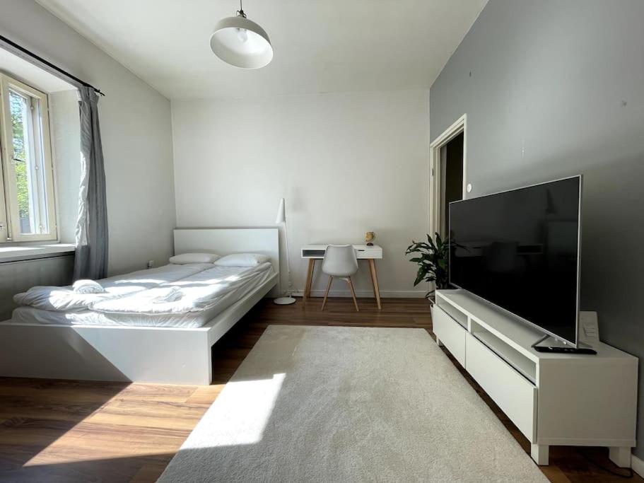 a white bedroom with a bed and a flat screen tv at Studio The Vibe / 25min to airpt & 5min to center in Helsinki