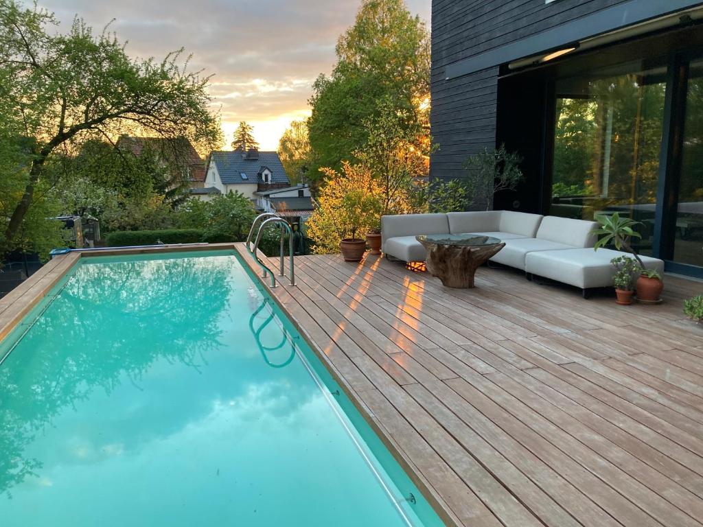 a swimming pool on a wooden deck with a couch on a patio at Poolvilla in Caputh