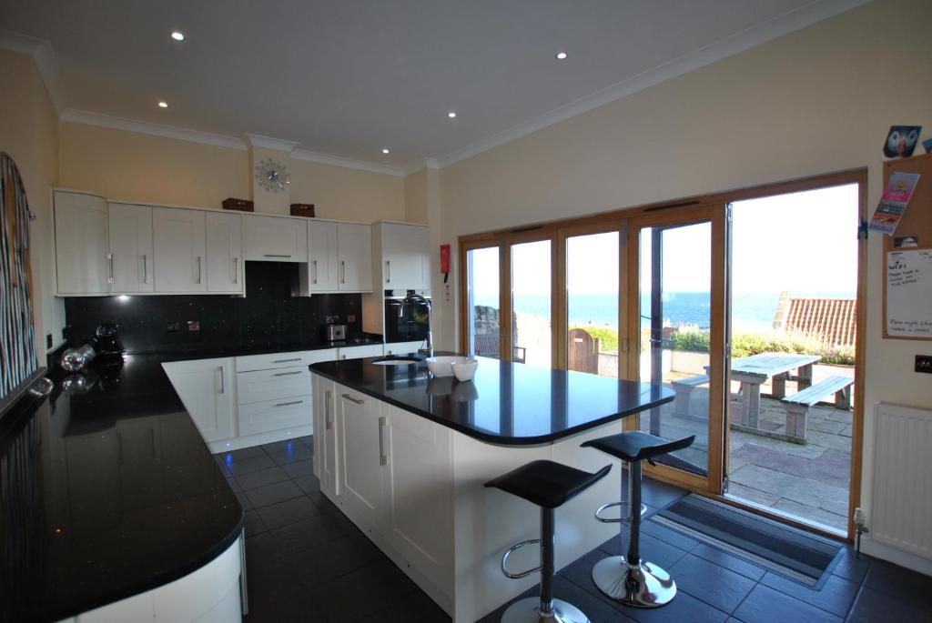 a kitchen with white cabinets and a black counter top at Anchor House Pittenweem - luxurious 4 bedroom in Pittenweem