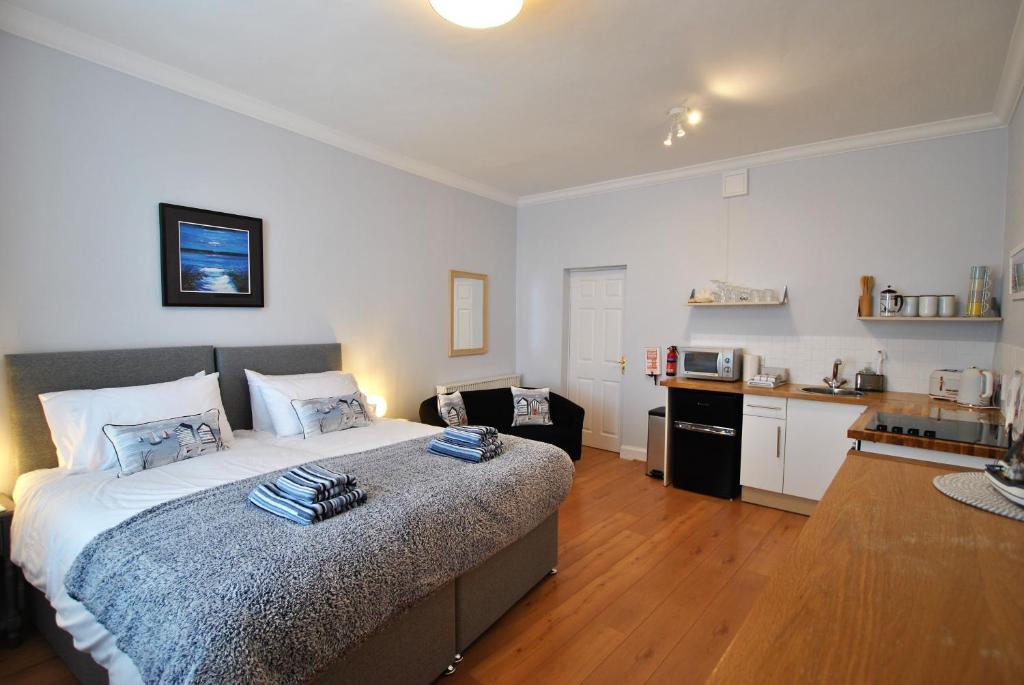 a bedroom with a large bed and a kitchen at Market Apartment- harbourfront studio Pittenweem in Pittenweem