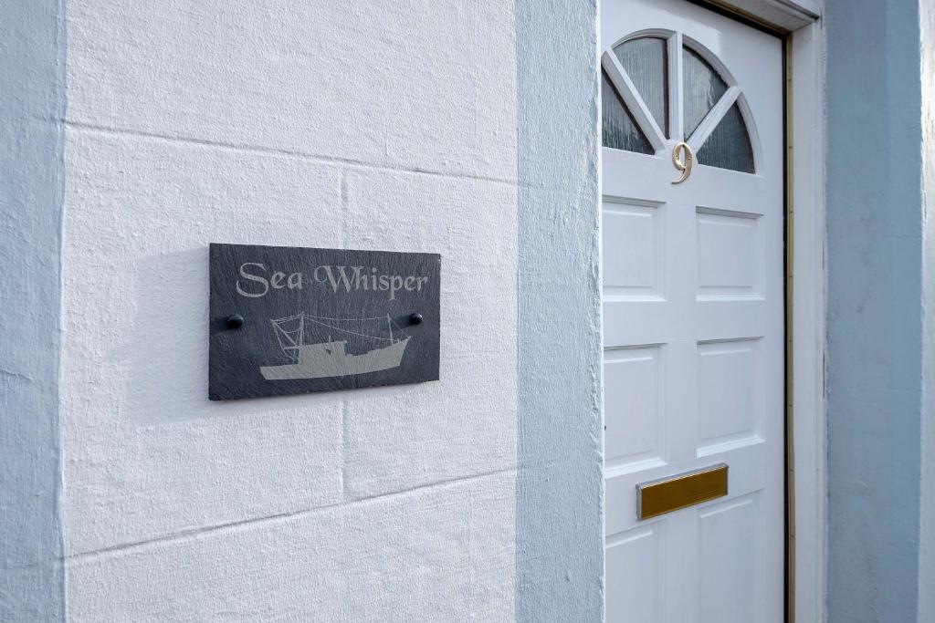 a sign on a wall next to a door at Sea Whisper- lovely home in charming village in Pittenweem