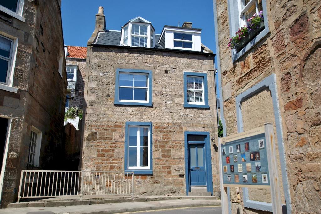 an old brick building with a blue door and windows at Puffin House- stylish home by the sea in Anstruther