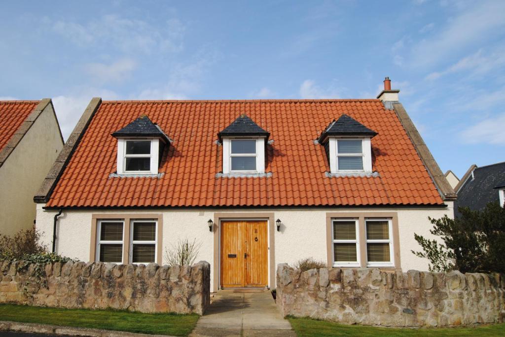 a white house with an orange roof at Orchard Cottage-spacious cottage in rural setting in Kilrenny