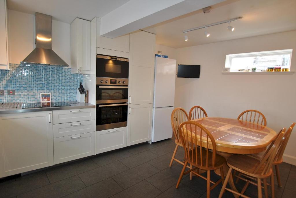 a kitchen with a wooden table and a kitchen with white appliances at Seaglass Cottage-family friendly home in East Neuk in Pittenweem