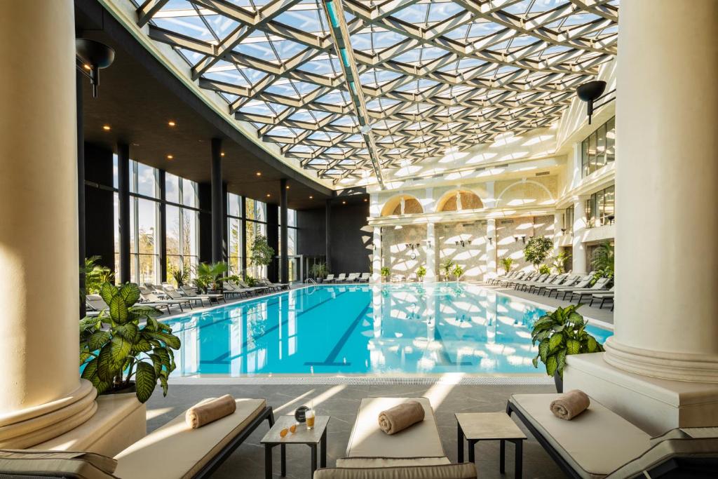 une grande piscine avec des chaises et un plafond dans l'établissement Kings' Valley Medical & Spa Hotel, à Kazanlak