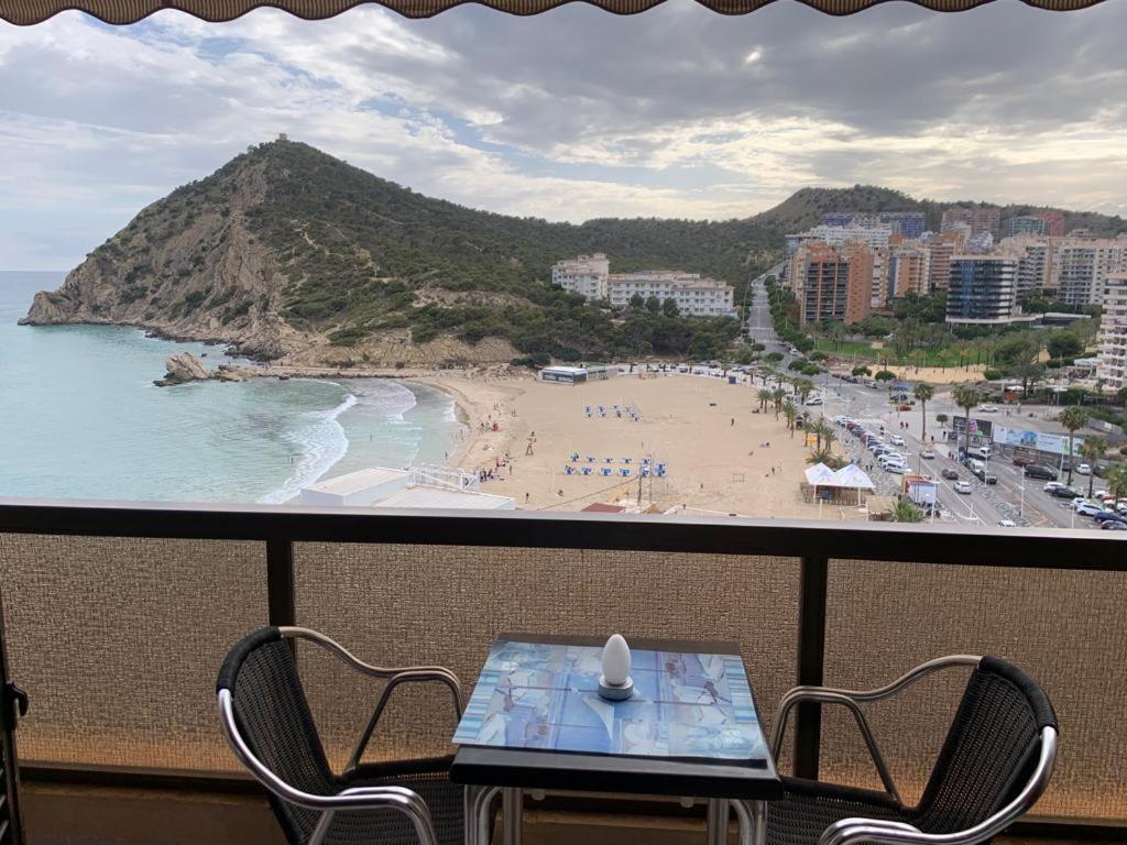 einen Balkon mit einem Tisch und Stühlen sowie einem Strand in der Unterkunft Apartamento en Cala de Finestrat - Edificio Atalaya 5º 10 in Cala de Finestrat