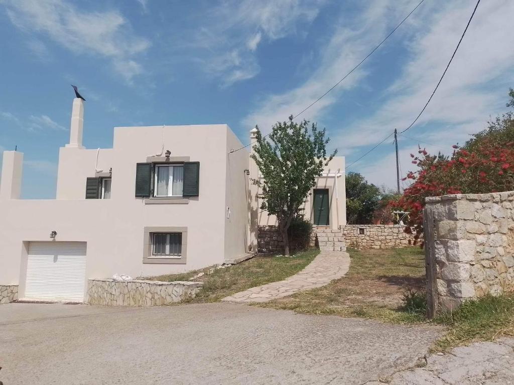 a white house with a stone wall next to a driveway at Ze Di Ma House in Kýthira