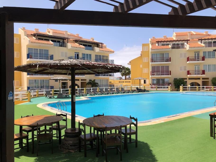 a pool with tables and chairs and an umbrella at Spacious 2 bed Apt with pool & sea views in Sal Rei