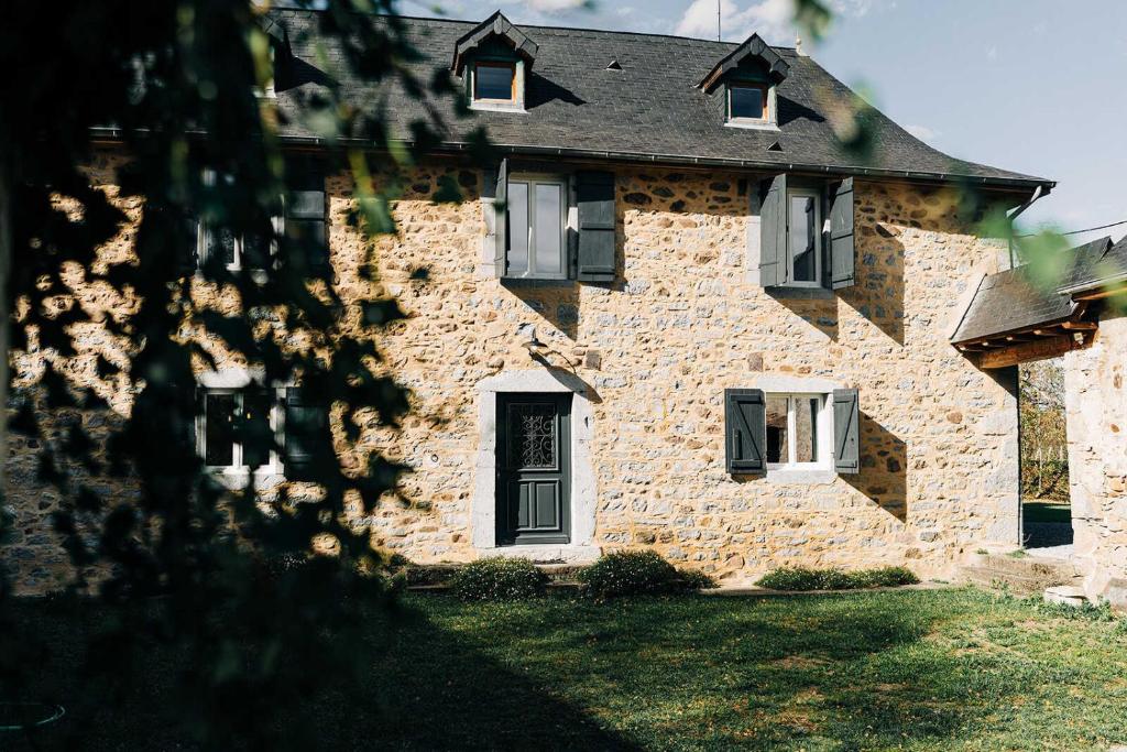 une maison en pierre avec une porte et des fenêtres noires dans l'établissement Le gout, à Lasseubetat