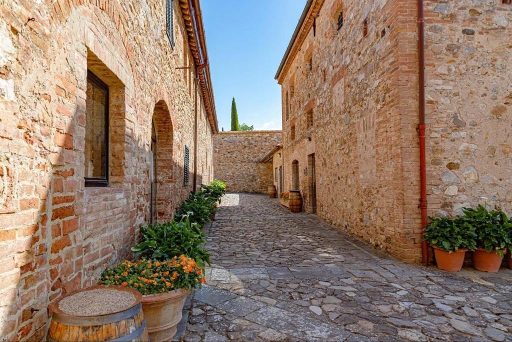 an alley in an old building with potted plants at La Foresteria di Castell'in Villa in Castelnuovo Berardenga