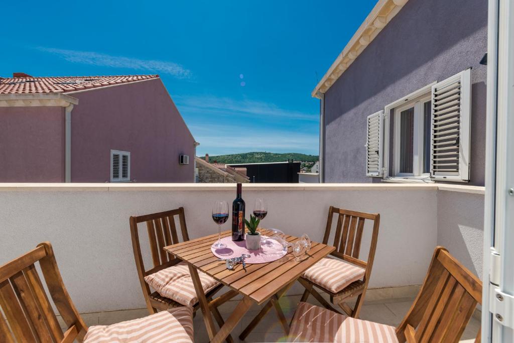 a table and chairs on a balcony with wine glasses at Apartments Lana in Mlini