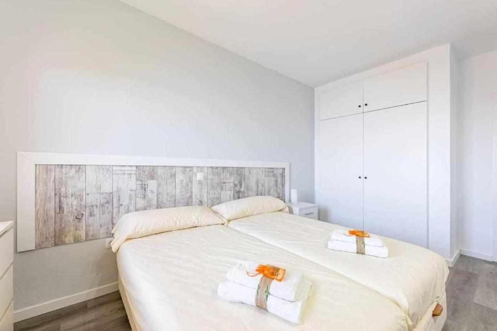 una camera bianca con un grande letto con due asciugamani di BENALBEACH APARTAMENTO con vistas maravillosas a Málaga