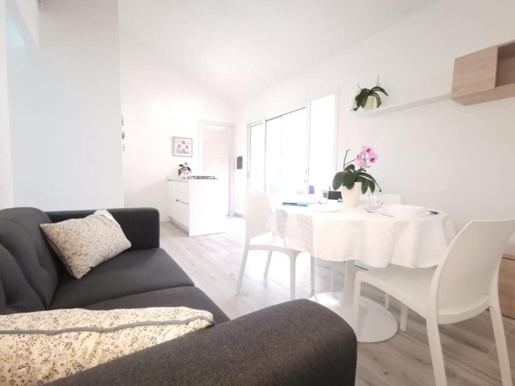 ein Wohnzimmer mit einem Sofa und einem weißen Tisch in der Unterkunft Appartamento due passi dal mare in Fort Village