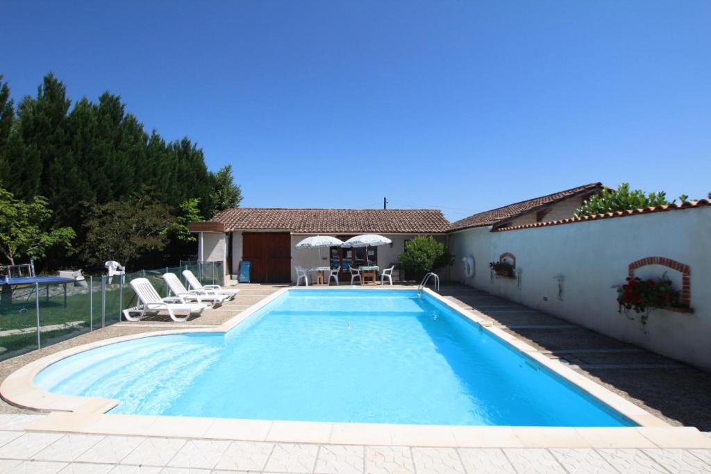 a swimming pool with chairs and a house at Baserian in Saint-Pé-de-Léren
