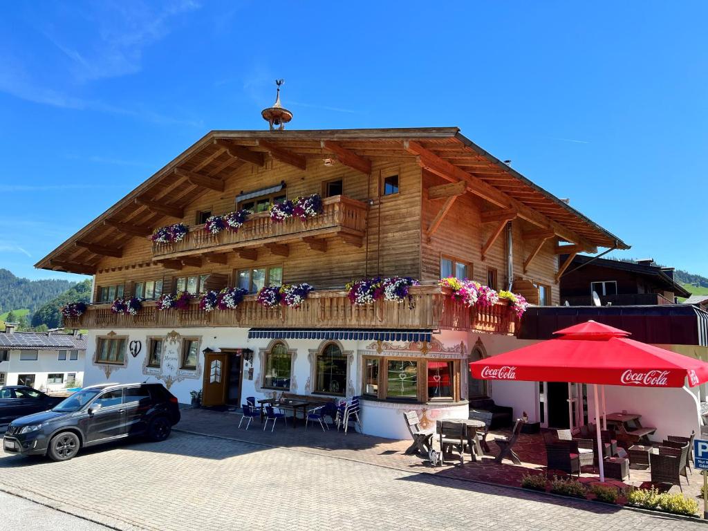 una casa in legno con balcone e una macchina parcheggiata di fronte di Haus Marjanne a Niederau