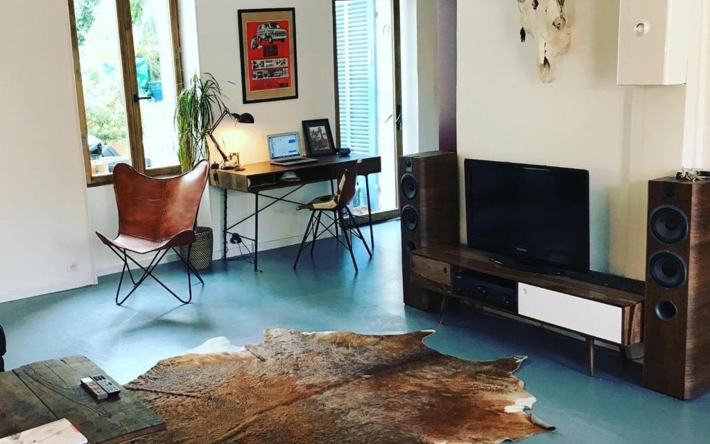 a living room with a table and a desk with a tv at Appartement chaleureux et atypique avec jardin à Marseille by Weekome in Marseille