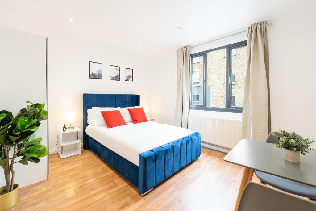 a bedroom with a bed and a desk and a window at King's Cross Apartments in London