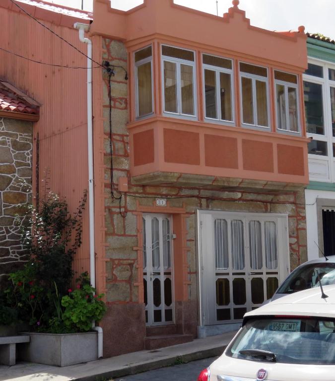 an orange house with a white car parked in front of it at CUCA in Muxia