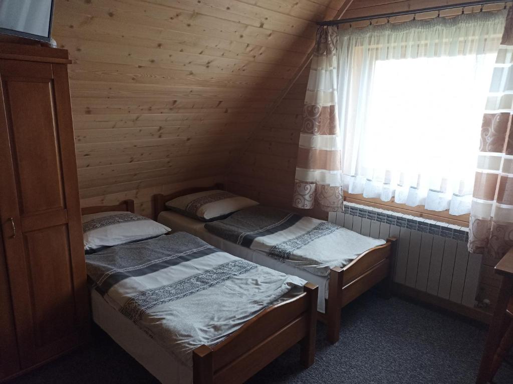 two beds in a room with a window at U Wyrostków in Gliczarów Górny