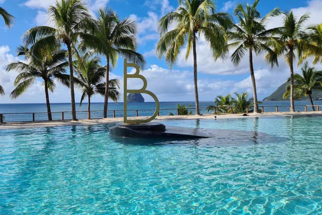 una piscina del resort con una grande lettera b in acqua di Studio vue mer et rocher du Diamant Antilles a Le Diamant
