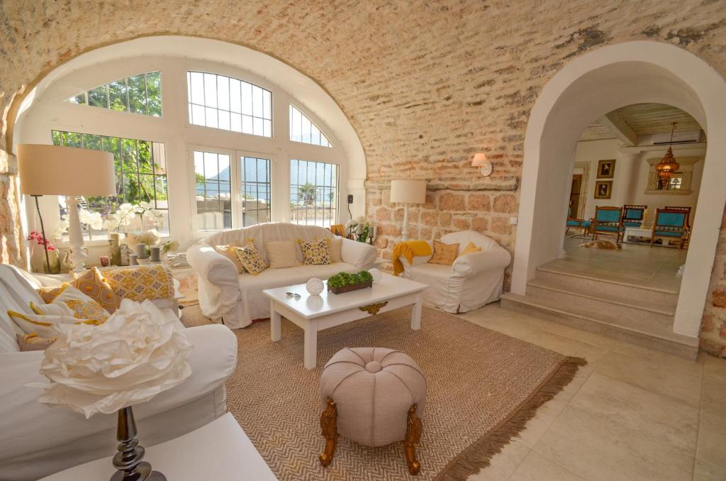 a living room with white furniture and a brick wall at Villa Bocca del Perasto in Perast
