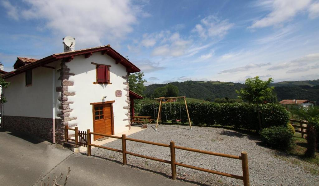 ein kleines weißes Gebäude mit einer Holztür und einem Zaun in der Unterkunft Etxe ondoa in Ascarat