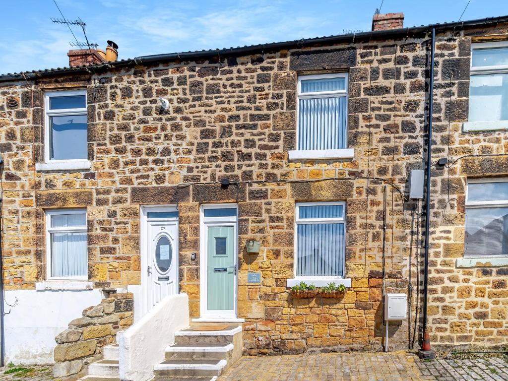 an old brick house with a blue door at Kew Cottage in Brotton