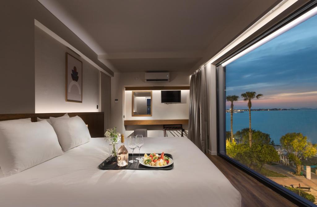 una habitación de hotel con una comida en una cama con una gran ventana en Kos Divine Hotel & Suites, en Cos