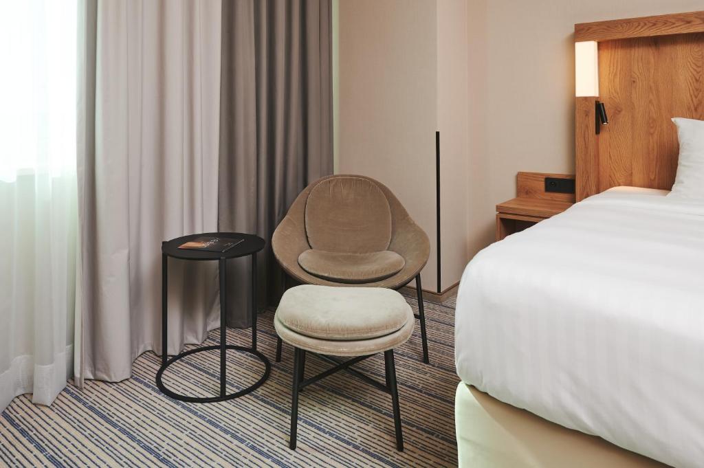 a hotel room with a bed and a chair next to a bed at Courtyard by Marriott Warsaw Airport in Warsaw