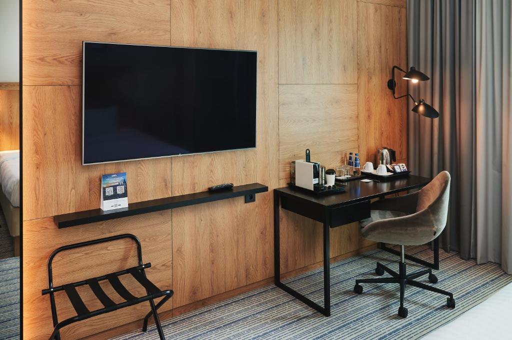 a hotel room with a desk and a television on a wall at Courtyard by Marriott Warsaw Airport in Warsaw