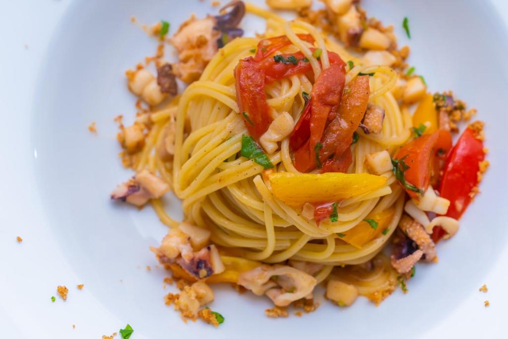 a plate of pasta with bacon and other vegetables at Hotel America in Marina di Camerota