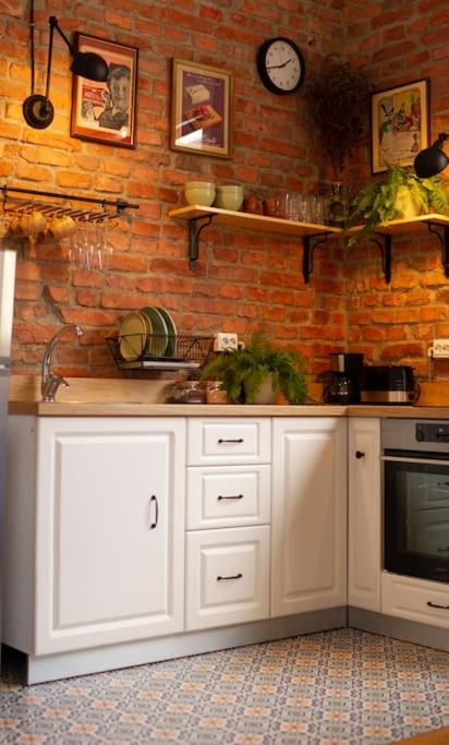 a kitchen with white cabinets and a brick wall at Central Park Apartment in Cluj-Napoca