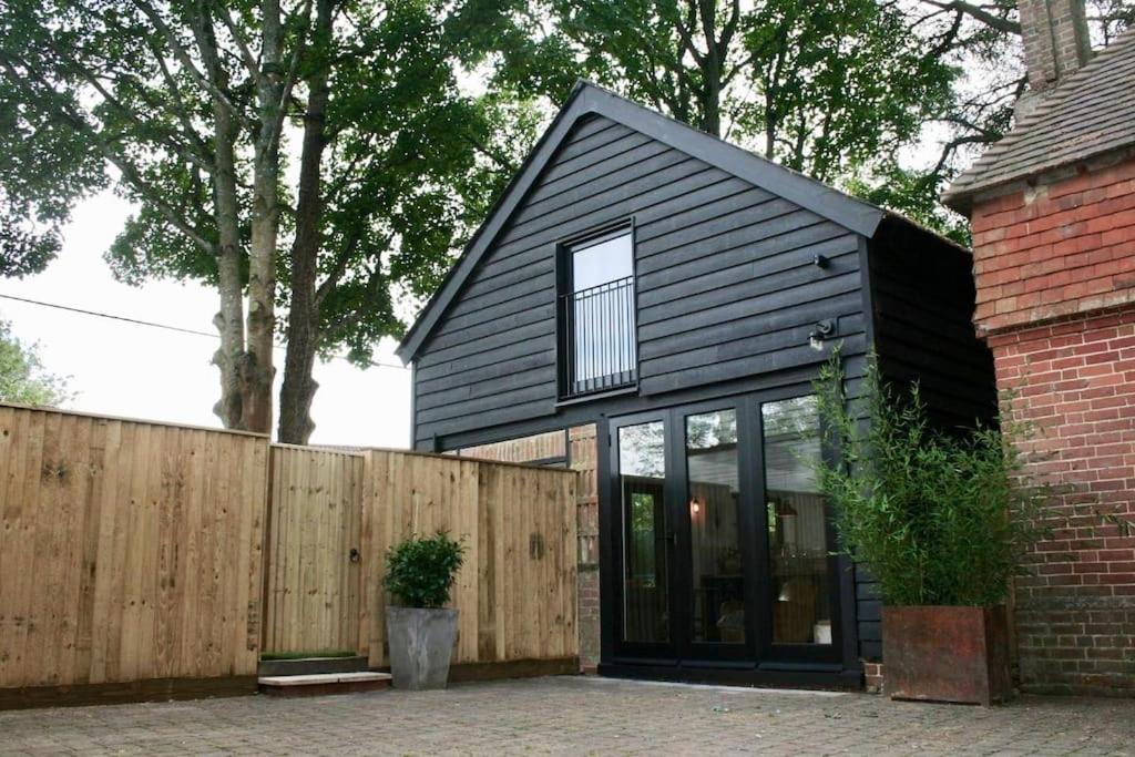 une maison noire avec une clôture en bois dans l'établissement The Post Barn, beautiful barn conversion 10mins from Winchester, à Sparsholt