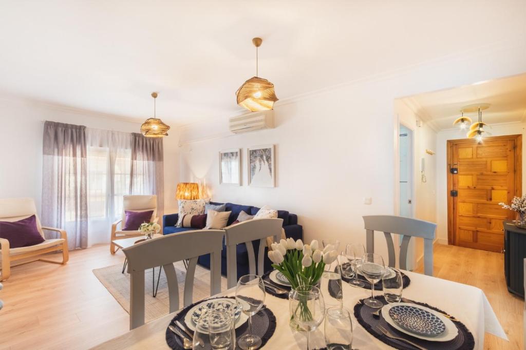 a dining room and living room with a table and chairs at Las Olas Chipiona in Chipiona