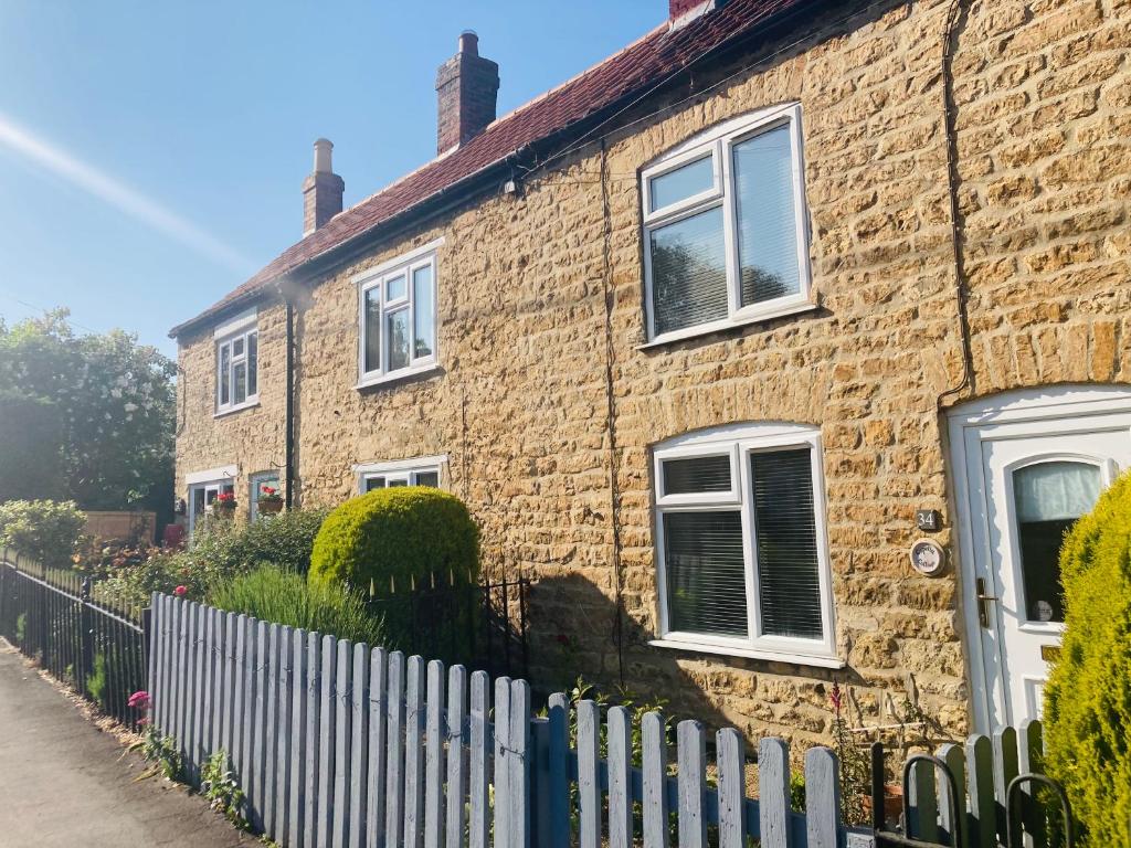 ein Backsteinhaus mit einem Zaun davor in der Unterkunft Cosy cottage four miles from Lincoln city centre in Lincoln