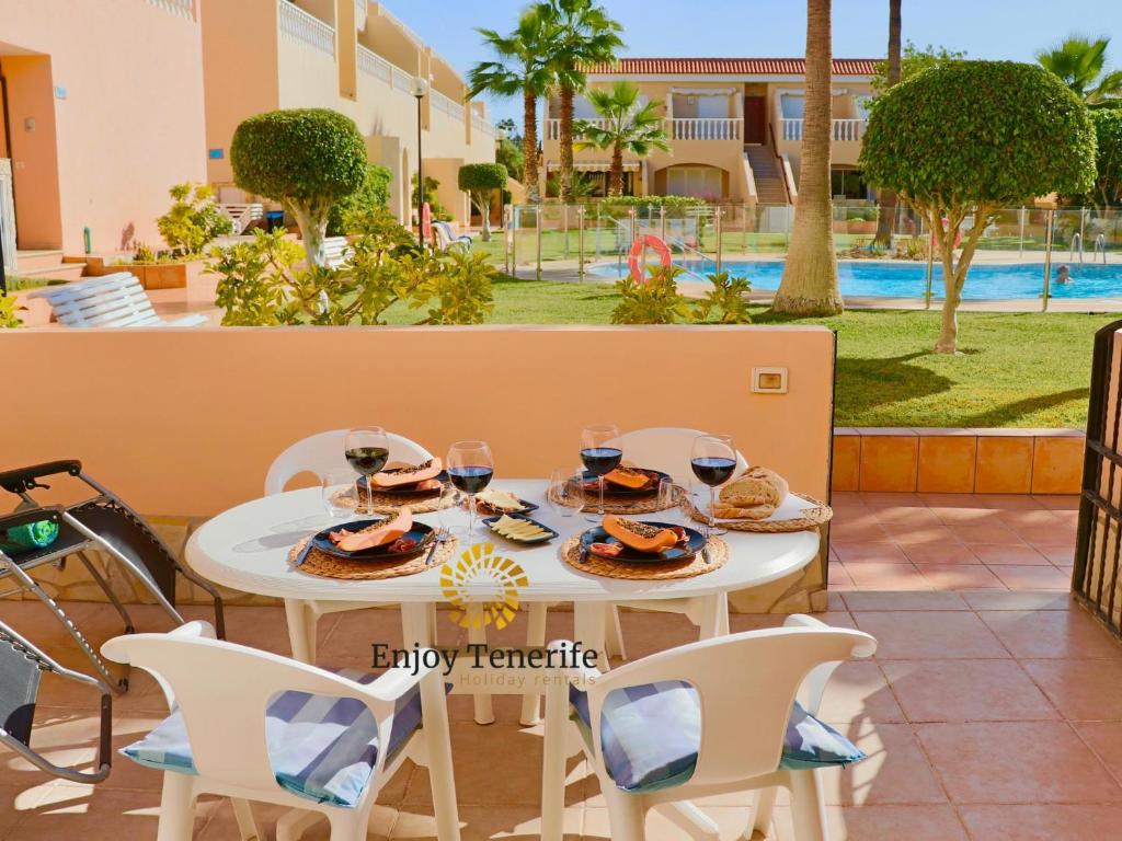 een witte tafel en stoelen met wijnglazen erop bij California Relax ALICE I POOL VIEW in Puerto de Santiago