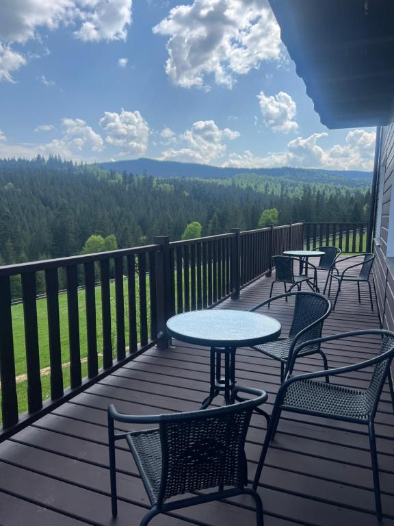 four tables and chairs on a deck with a view at Мелодія Гір in Vorokhta