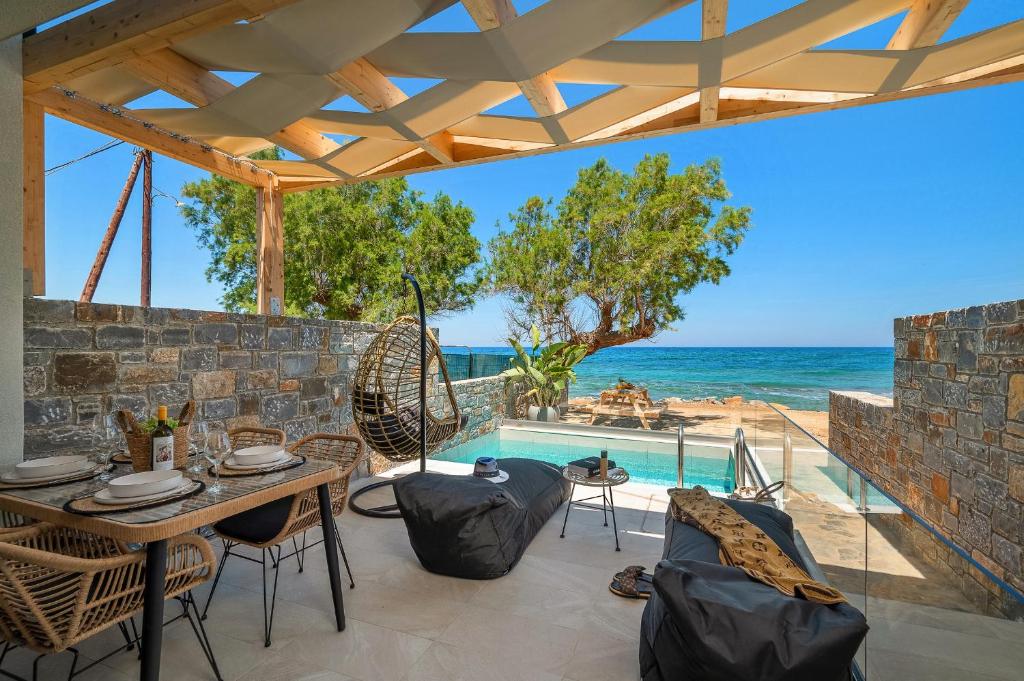 eine Terrasse mit einem Tisch und Stühlen sowie einem Pool in der Unterkunft Milatos Seaside Suites in Mílatos